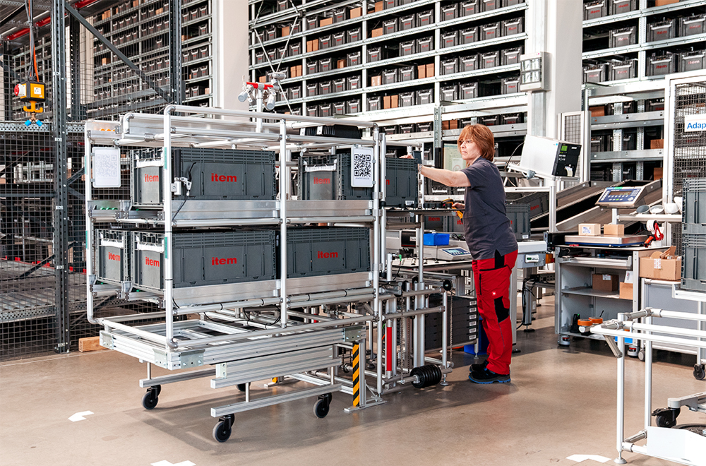 A staff member loads materials into a rack superstructure on an amr base frame