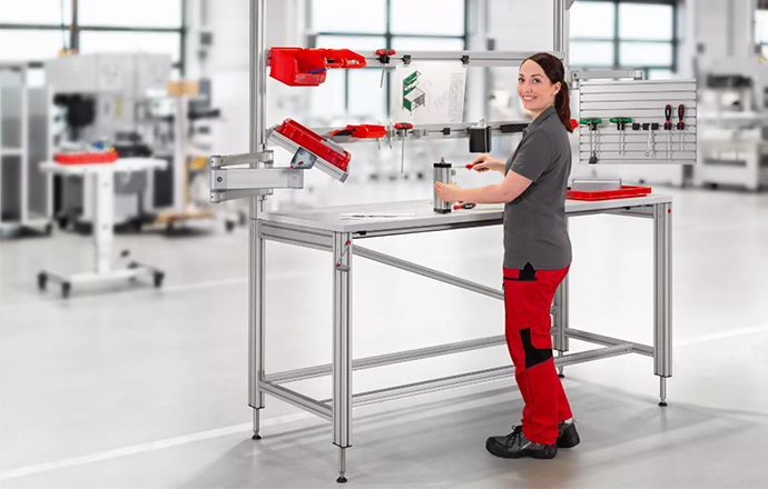 An item team member stands at a height-adjustable work station developed using item Work Bench System, Lean Production, and Table Column Sets K