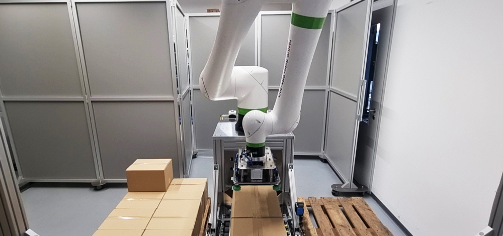 Automatisierte-verpackungsanlage-fuer-maximale-flexibilitaet-item-blog-bild-im-beitrag-4 Un cobot fanuc recogiendo una caja durante el proceso de paletizado
